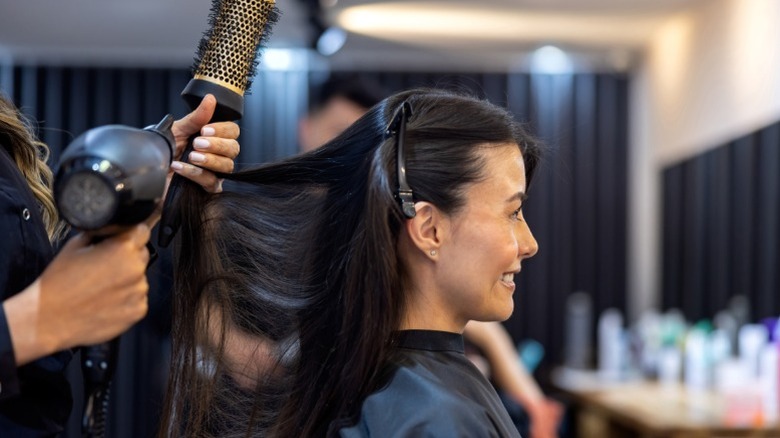 A woman smiles as her hair is blown out