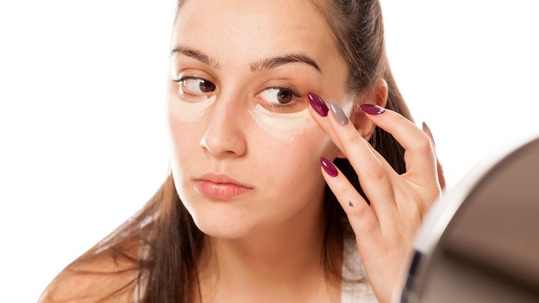 Woman applying concealer under eyes