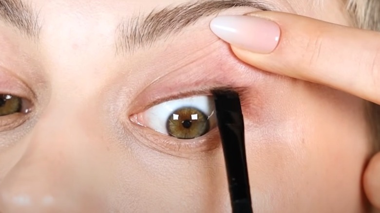 A woman tightlining her eyes