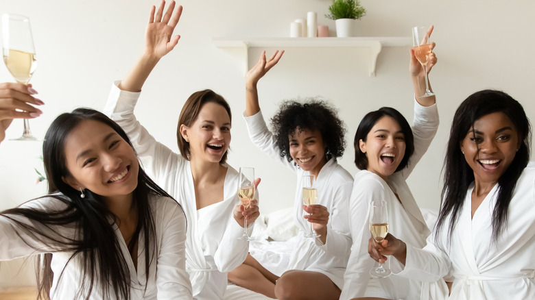 bridesmaids cheersing in bathrobes