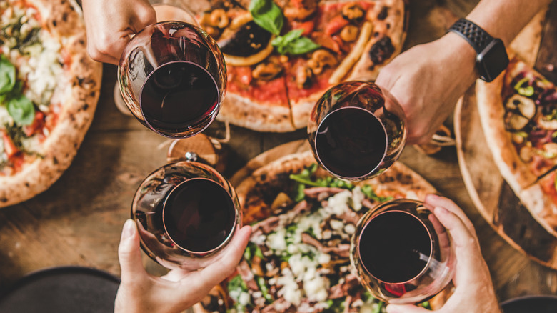 wine and pizza being cheered by friends