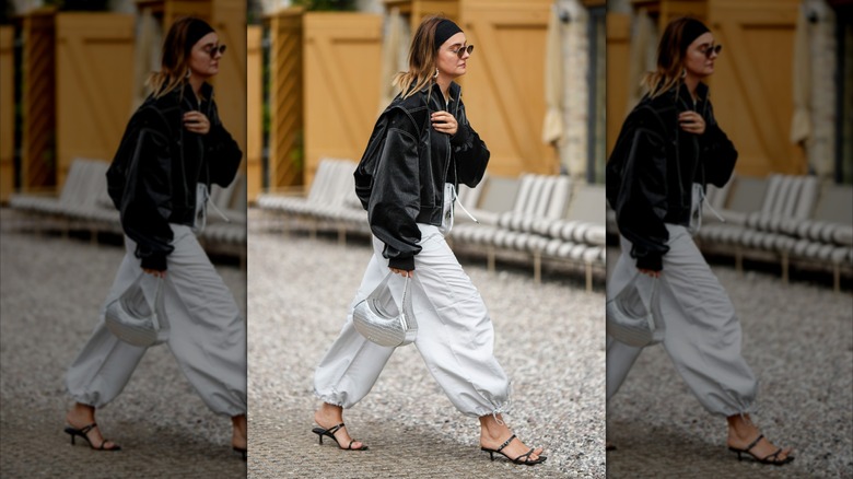 A woman wearing baggy pants with strappy heels.