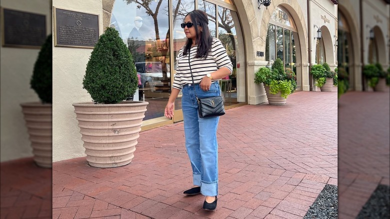 A woman wearing cuffed jeans with ballet flats.