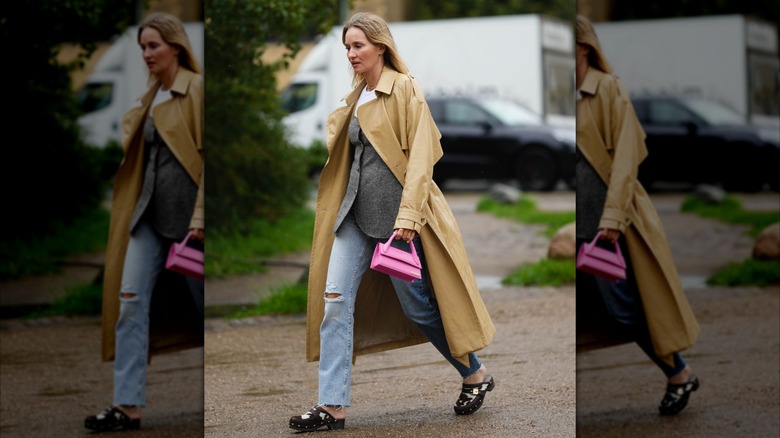 A woman wearing distressed jeans and clogs.