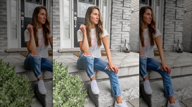 A woman wearing mom jeans and white sneakers.