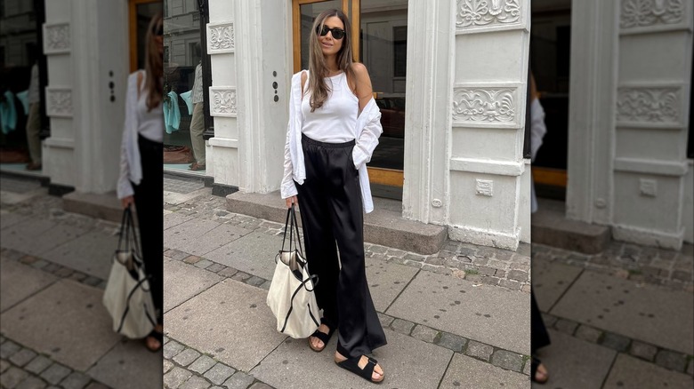 A woman wearing silk pants with buckle sandals.