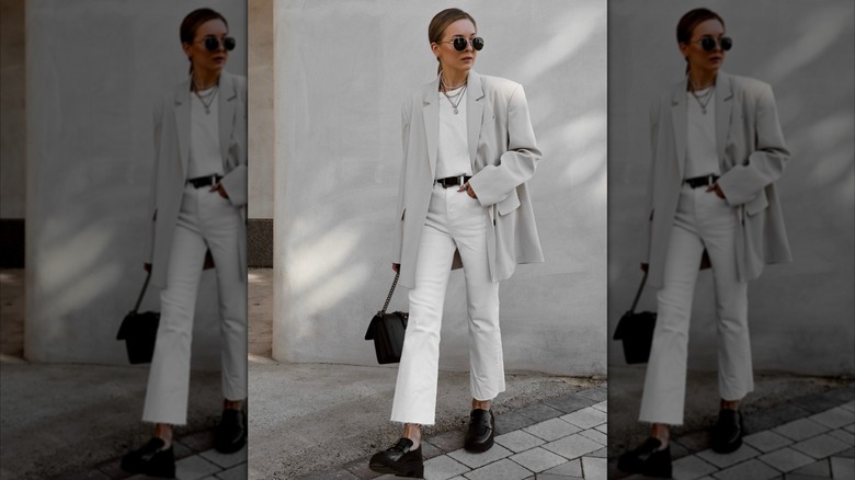 A woman wearing white pants with loafers.