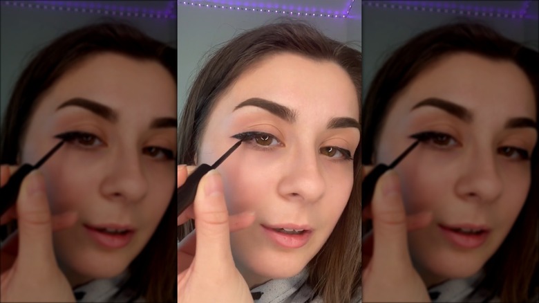 woman applying downturned eyeliner