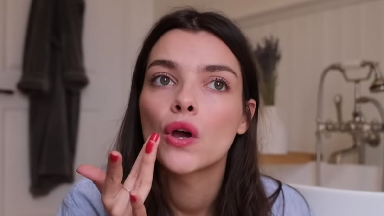 Applying red lipstick with fingers