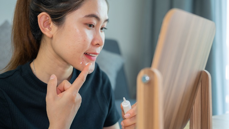 Woman applying cream to chin