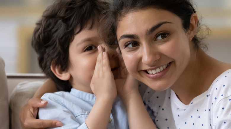 son whispering into his mother's ear