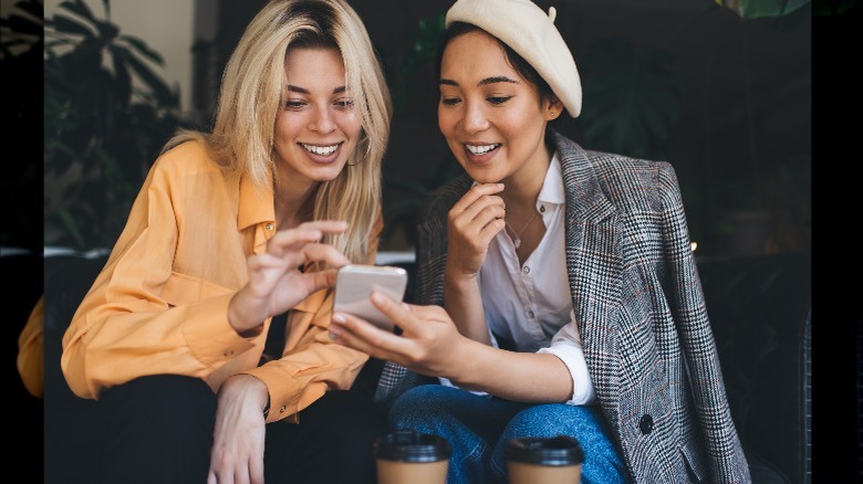 Friends smiling, going through phone