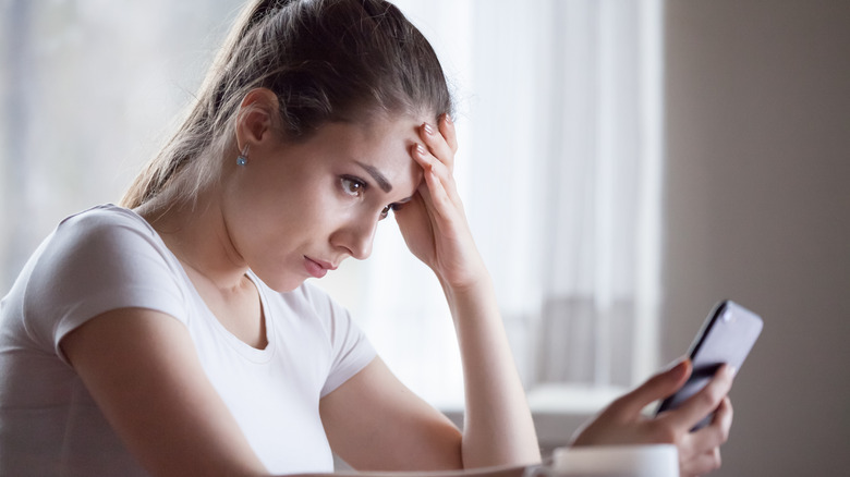 Woman looks frustrated while holding phone 