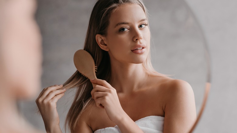 Girl brushing blond hair in mirror