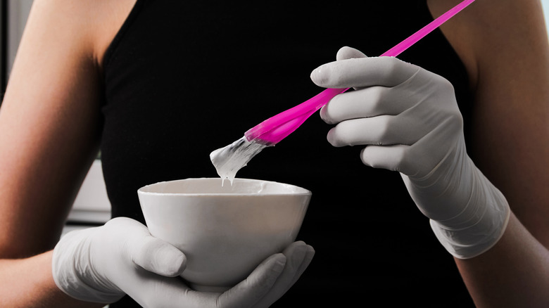 Gloved hands holding dyeing brush