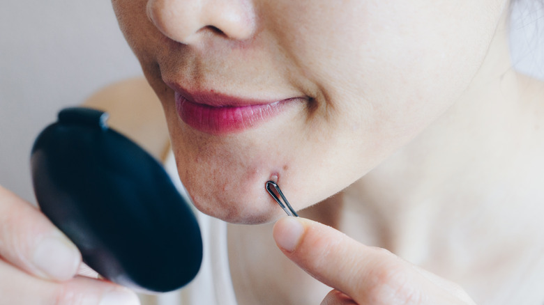 Woman pressing comedone extractor to chin