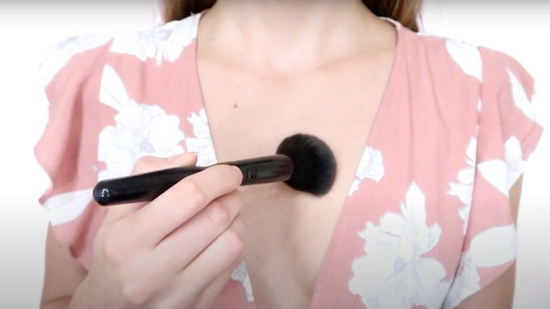 woman applying powder to chest