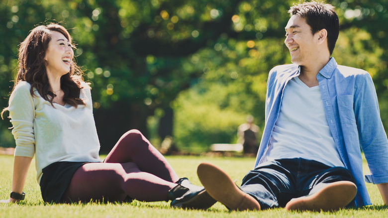 A happy couple sitting on grass together