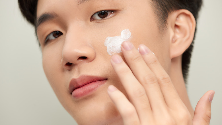 young asian man applying sunscreen