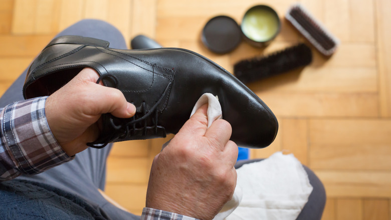 person conditioning leather shoes