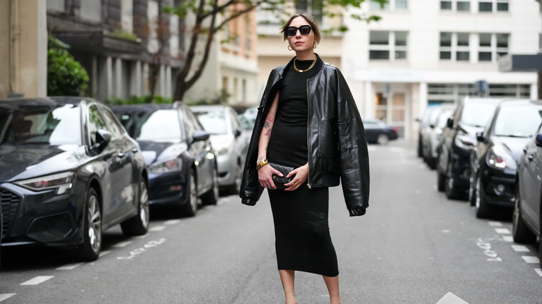 A woman wearing a sheath dress with a leather jacket and sunglasses