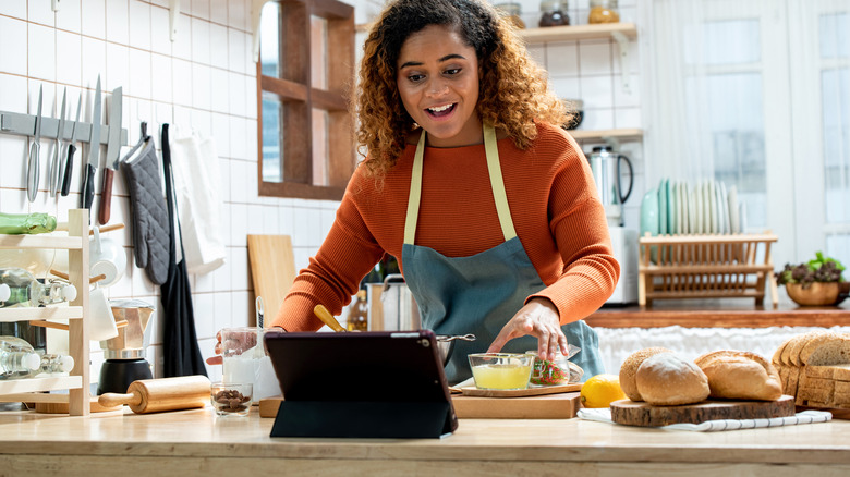 Woman cooking near laptop
