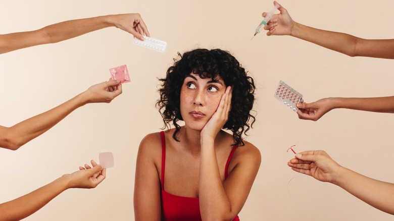 Woman surrounded by hands holding birth control