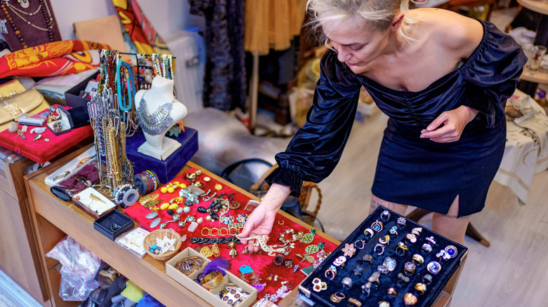 A person browsing through a thrifted jewelry store assessing a piece