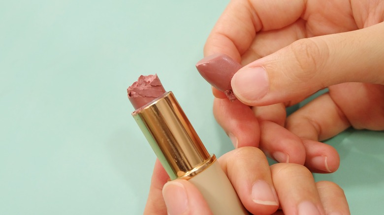 Hands holding dried out lipstick