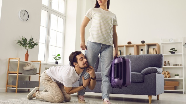 Man clinging onto girlfriend's leg
