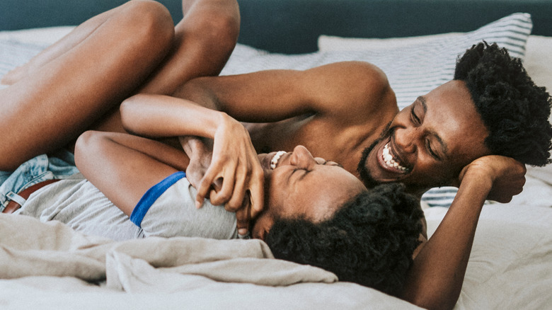 Black couple laughing in bed