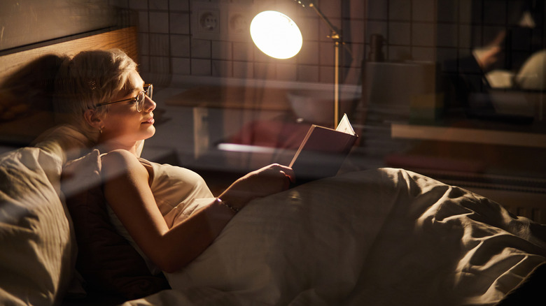 woman reading book in bed