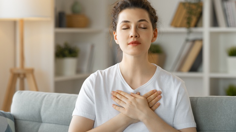 Woman holds hands over heart