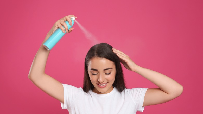 woman applying dry shampoo to her hair