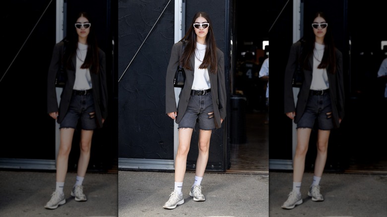 A person wearing distressed dark-denim shorts and a blazer