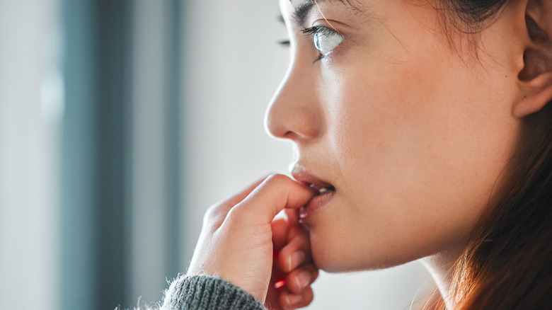 woman biting nails while stressed