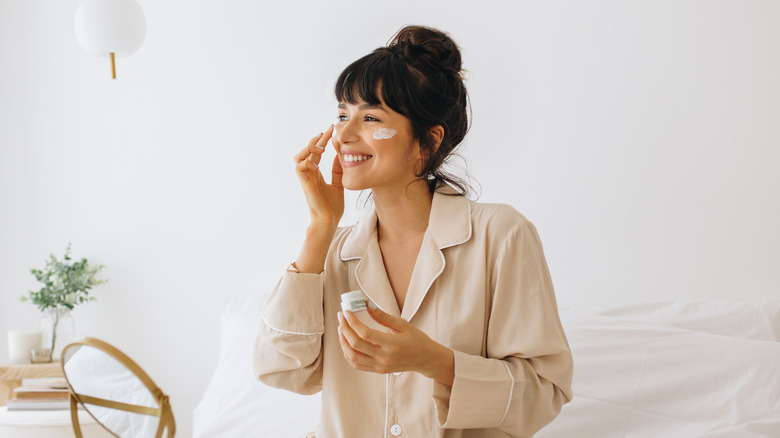 A woman applying face cream 