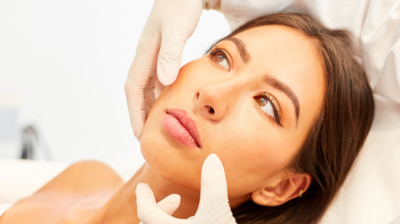 gloved hands touching woman's face