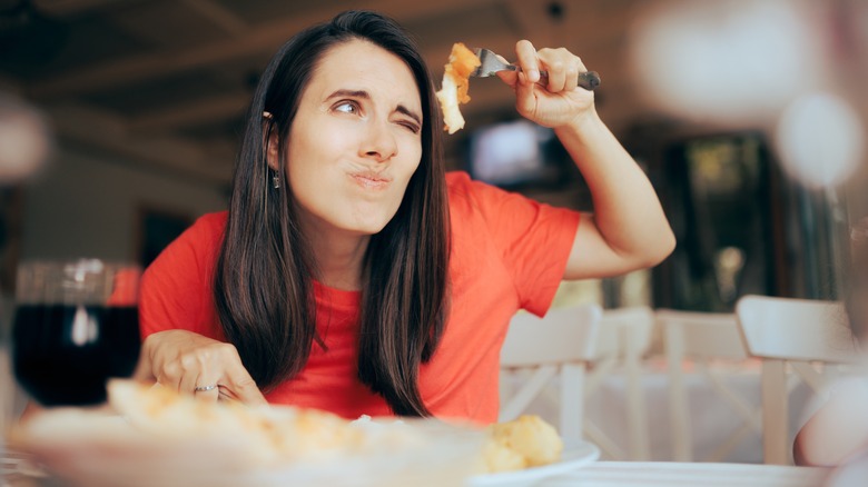 Woman peering fussily at food
