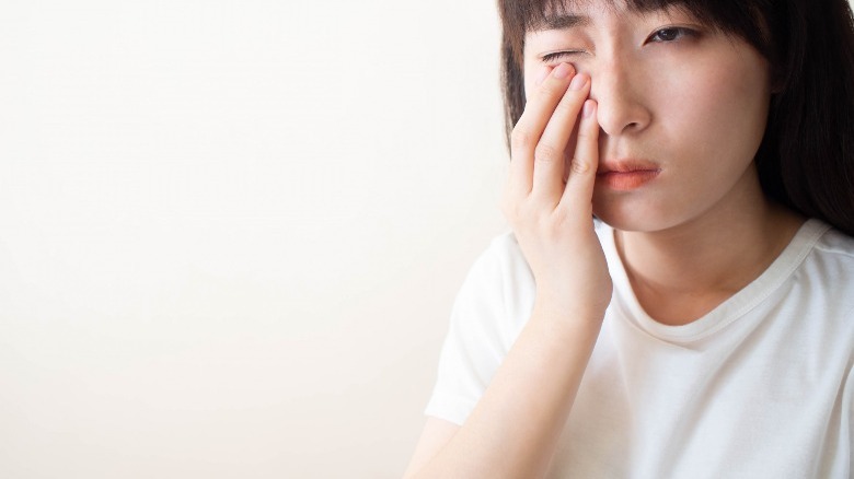 Asian woman rubbing eye