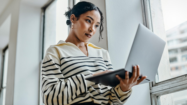 Woman standing, using laptop