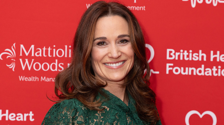 Pippa Middleton posing in front of a red media wall at a charity event