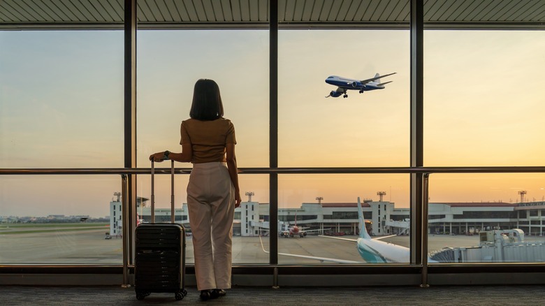 woman watching plane from an airport window