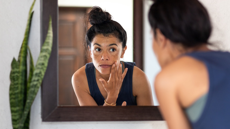 woman applying skincare in mirror