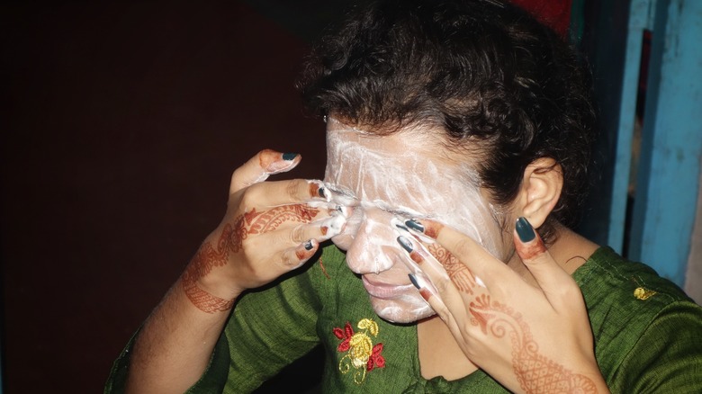 Woman rubbing face wash on eyes
