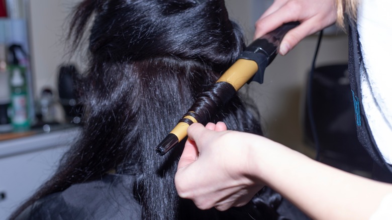 hair stylist curling hair with wand
