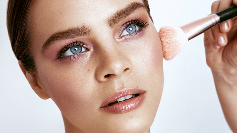 Closeup of makeup artist applying highlighter