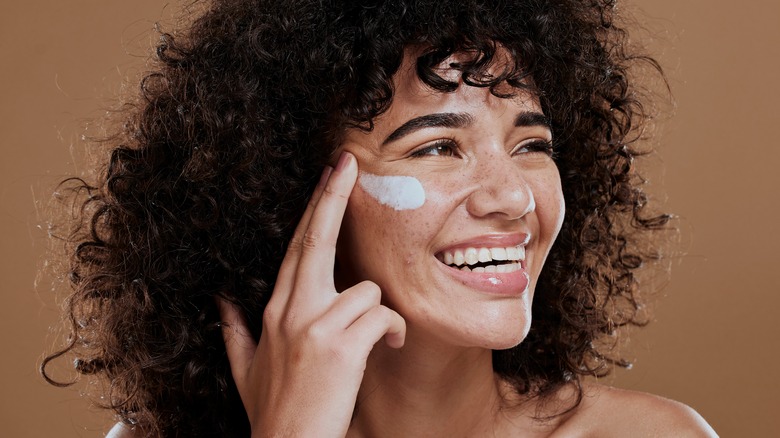 smiling woman applying sunscreen
