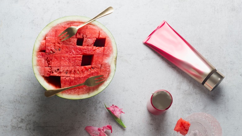 watermelon with forks next to skincare bottles