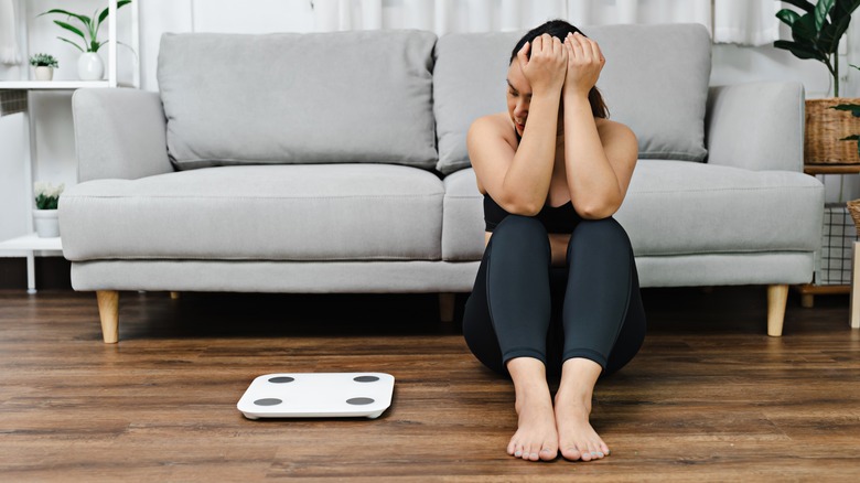 Upset woman next to scale